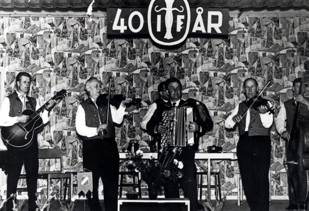 Orkesta spelmanslag spelar i bygdegården när Orkesta IF firar 40-års jubileum.  På scenen står fr v Lennart Jansson gitarr, Erik Holmberg fiol, Harry Fransén dragspel, Åke Matsson dragspel, Sven Wahlström fiol och Hasse Forsberg bas