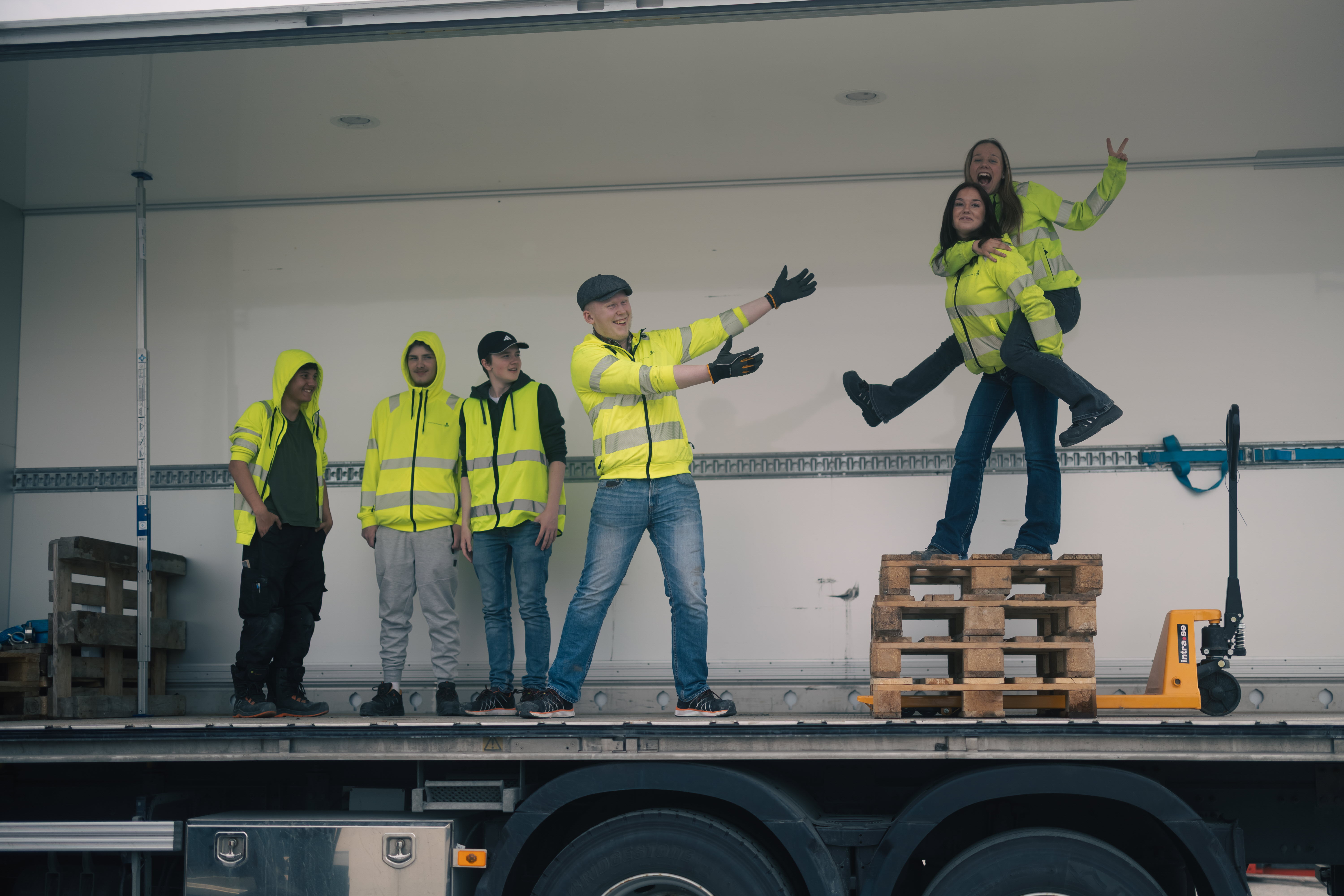 Sex elever poserar tillsammans  inne i lastbilen vars ena vägg fällts ner, väl parkerad.