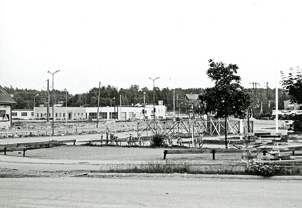 På andra sidan järnvägen syns från vänster hörnet av Vallentuna järnvägsstation, som revs strax efter att bilden togs, Vallentuna motor, Elverket. Till höger om Vallentuna motors lokaler syns Röda skolan.