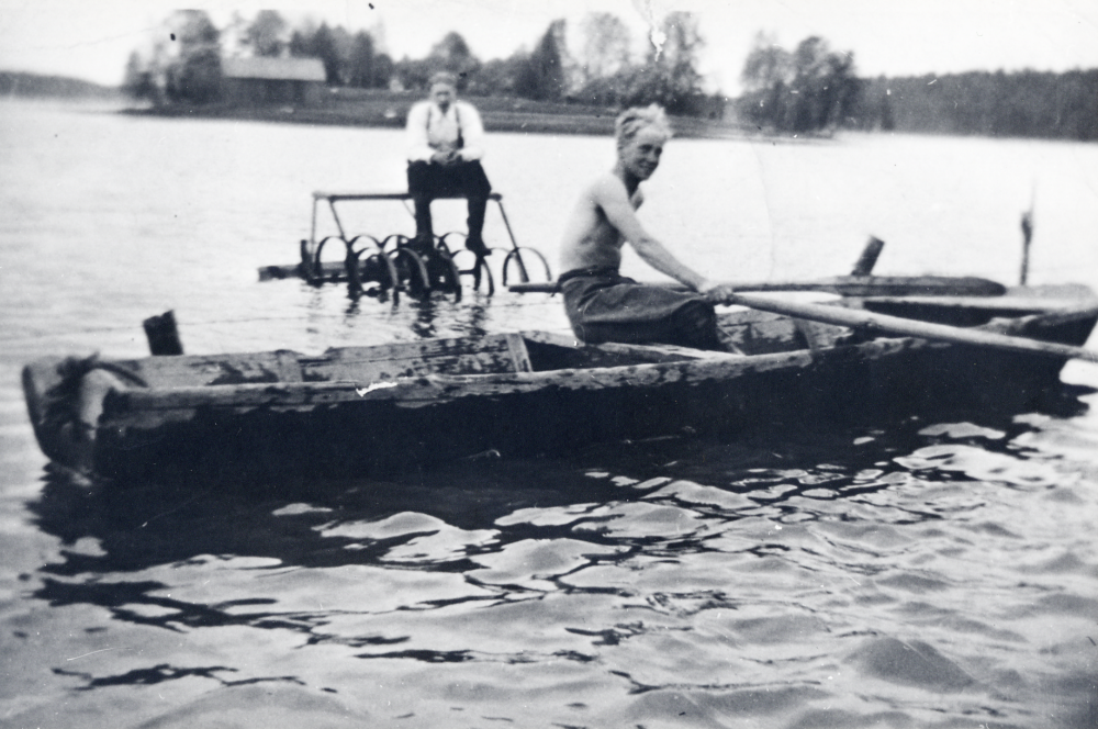 Hederviken har blivit sjö på nytt genom översvämning I roddbåten sitter Bengt Billefält och Sven Billersjö. Ladan i bakgrunden tillhör Lövsta säteri