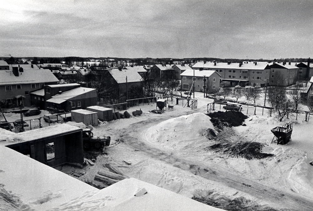 Förvaltningshuset  Tärningen  byggs.  Foto över omgivningarnas från det ännu ej färdigbyggda huset mot sydväst. Längst t v syns baksidan av  Handelsbankens hus  samt  Succé Färg- och tapetlager   T h om dem gamla skomakare Gustavssons villa, numera  Salong Allé  Det lilla ljusa huset tillhör  Lennart Karlsson  därbakom  flerfamiljshus längs  Allévägen