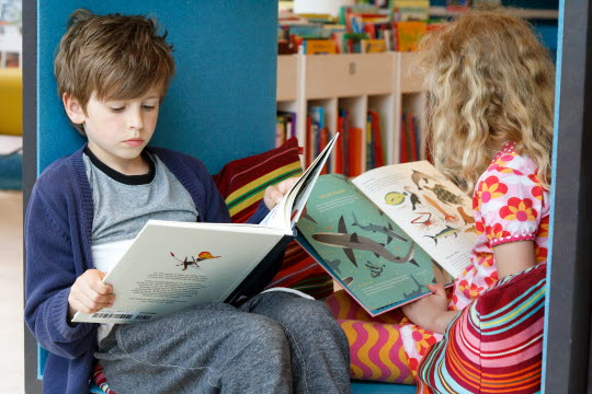 Två barn som sitter och läser böcker
