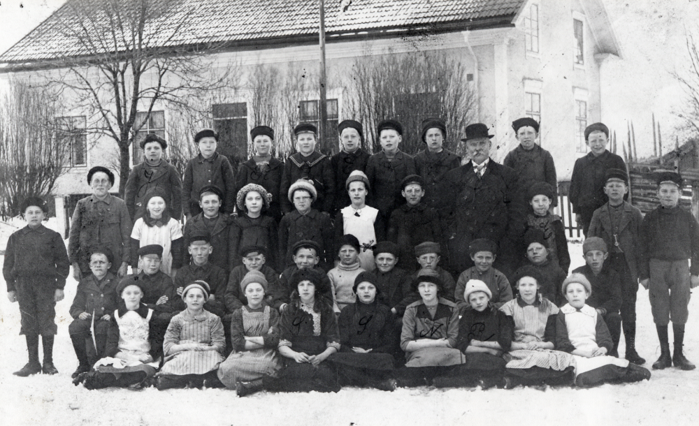 Läraren  Per Ferdinand Torell  tillsammans med skolbarnen framför  Klockargården  I främre raden nr 4 fr v  Stina Öberg  nr 5  Signe Österberg  och nr 6  Nancy Karlsson  Rad 3 nr 3 fr v  Lilly Jonsson