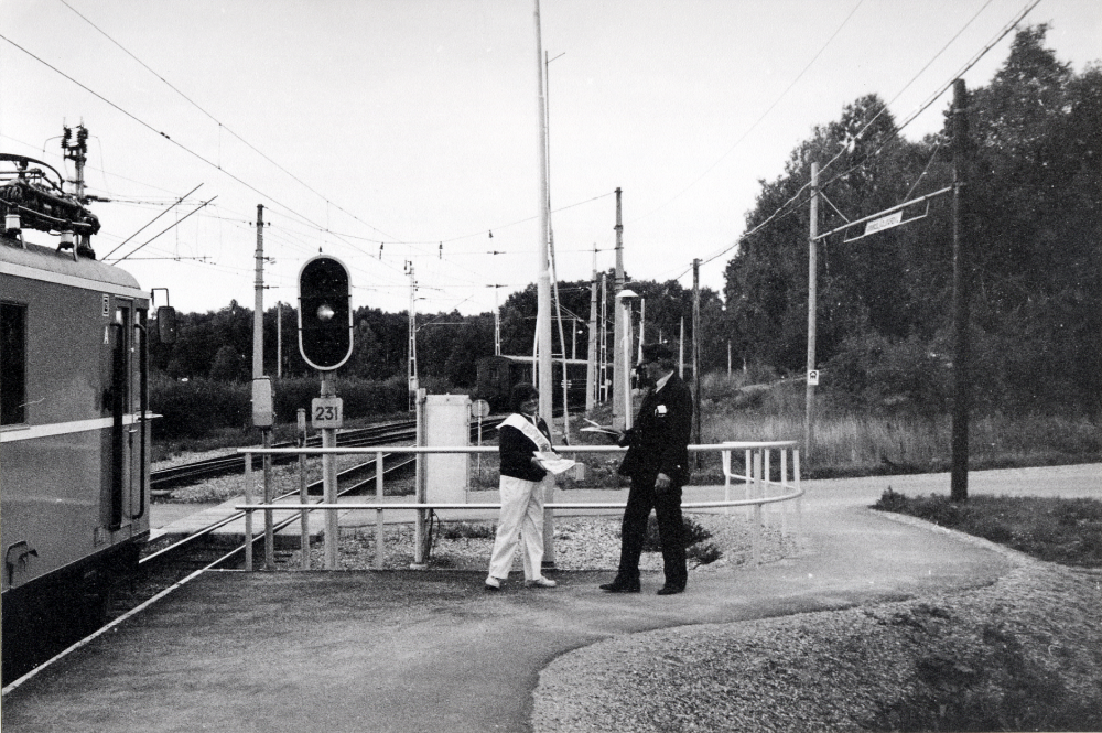Vallentuna bibliotek delar ut Läsenären, en tidning utgiven av Länsbiblioteket.  Ett lok står på stationen på väg mot Stockholm.  Gun Hillbo ger konduktören Vokadin Zoban ett exemplar av tidningen