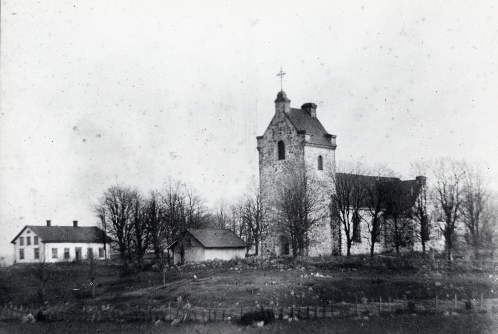 Vallentuna kyrka. Den vita byggnaden är Klockargården, skola 1864-1910. Bårhuset ligger nedanför kyrkoingången