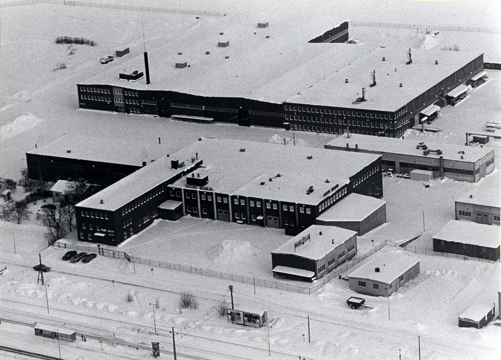 Flygfoto över Tellus-Maskins industri i Vallentuna. Vägen framför industrin är Industrivägen och i förgrunden spåren till Roslagsbanan. Den vita byggnaden t h om Tellus är K S Karlssons smidesverkstad, Sme-Kalle