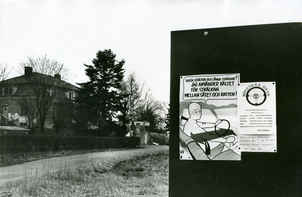 Anslagstavlan vid den lokala körgården våren 1973. Skylt till höger: "Precisionskörning med bil, öppen för alla osv." Handtextad skylt längst ned till höger lyder "Kvalificering i Vallentuna, Söndagen den 15/7 kl 10-14, Körgården Åby gata (tegelbruket), MHF, VMK, TSK"
•Fotografiet ingår i bildserien ”Vardagsliv i Vallentuna kommun” av Rachael Gough-Azmier & Gunilla Blomé, Haga Studios HB.