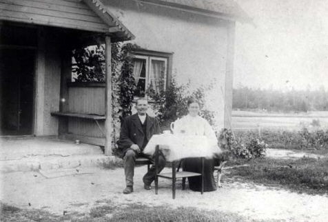 En man och en kvinna som sitter vid ett bord framför ett hus