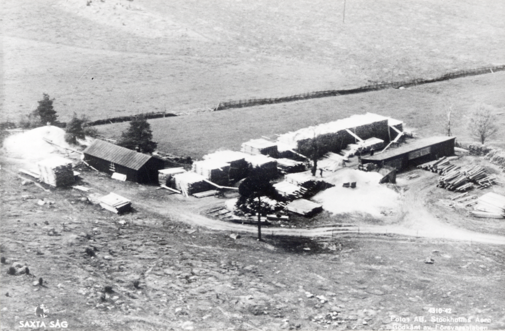 Saxta såg.  Som mest fanns sex anställda. På bilden ligger hyvelhuset t v och såghuset t h. På vintern gjordes inköp, rotposter och huggning. På våren sågade man, under sommaren torkades virket och på hösten var det hyvling och försäljning. Ca 7-8000 stockar sågades varje år. Från Saxta levererades virke till Tyskland under 1940-talet och sågen var i full gång fram till 1960.