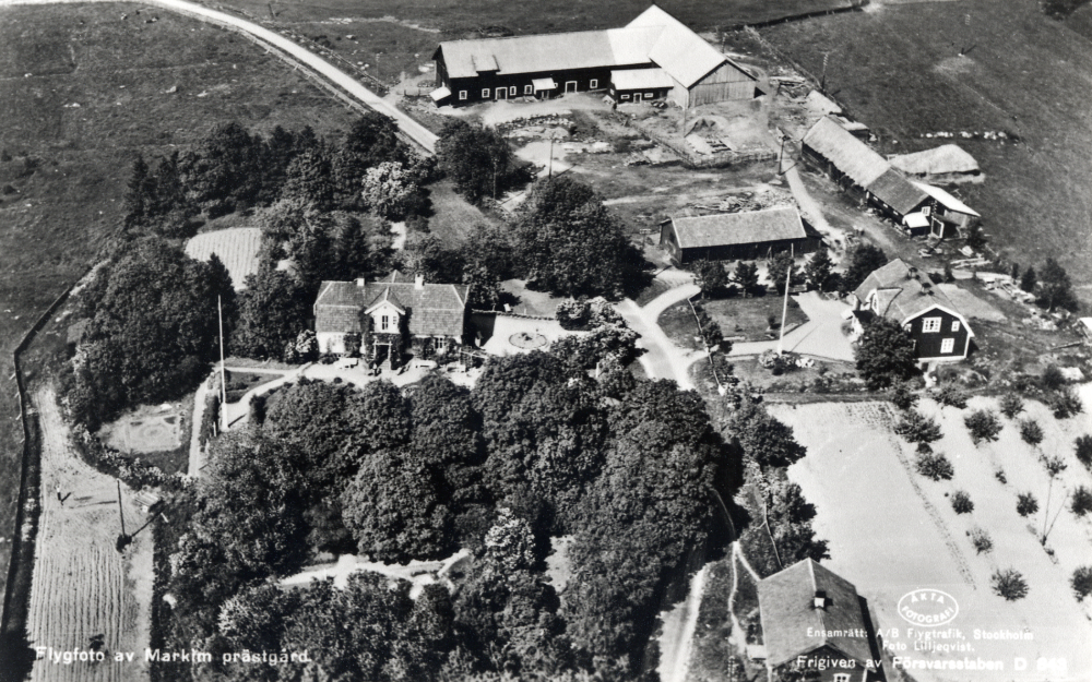 Vy över Markims prästgård med ekonomibyggnader.  Flygfoto, kopia av vykort.

Uppgift om fotoår saknas.