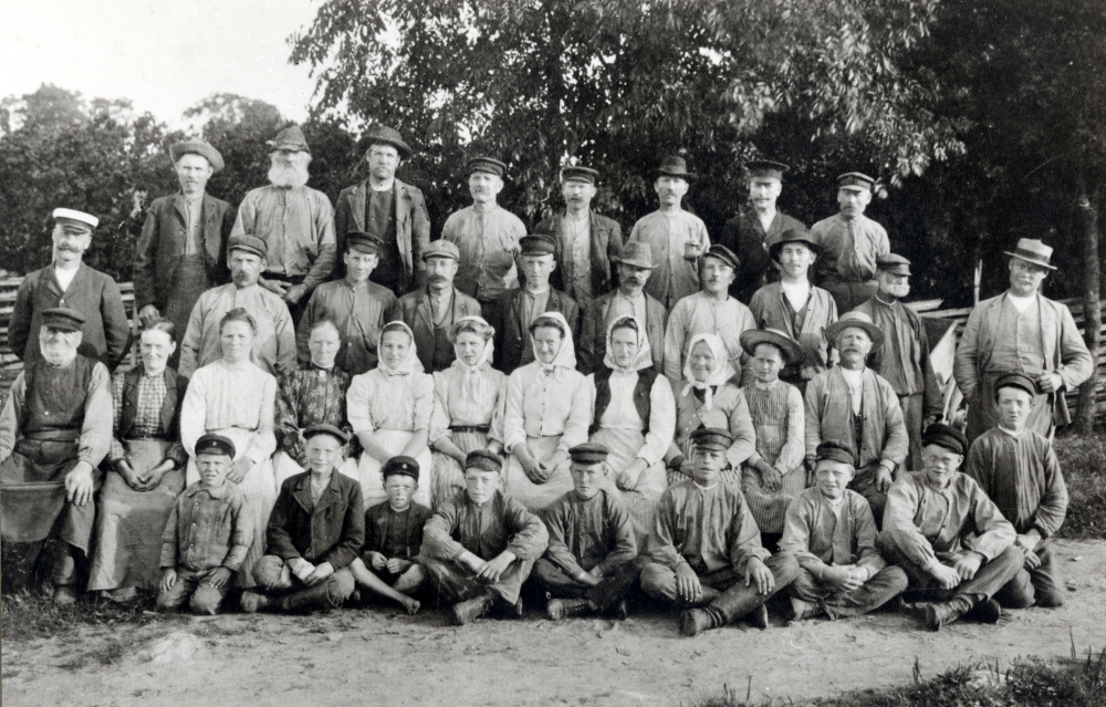Lindholmens gård. Övre raden fr v Gustaf Frück, Anders Kjellin, Hjalmar Johansson, Karlsson, Lundin, Erik Söderberg, Hellström kusk och Alfred Eklund. Rad 2 Erik Gustaf Ström, Karl Erik Lundkvist, Karl Andersson, Otto Jansson, Edvin Andersson, Albert Jansson, Karl Kraft, Gunnar Jansson, Jan Jansson, Axel Lundkvist trädgårdsmäst. Rad 3: Andersson oxstillare, Mina Andersson, Matilda Jansson, Sofia Söderberg, Adèle Kraft, Elsa Gustafsson, Anna Andersson, Elin Jansson, Johanna Frück, och Sara Eklund. Rad 4: Knut Johansson, Sjöman, Rickard Söderberg, Oskar Jansson, Edvard Lundkvist, Kuno Fransén, Tyko Ström, Ragnar Sjöman och Georg Svensson. Tillägg av Martin Linder våren 1987. 1911 arbetade man under lagen om städsla och lagen om husaga. På gården arbetade dagsverkstorpare och statare. Kvinnorna gick under betäckning hjon liksom pojkarna när de arbetade. Hur duktig en kvinna än var, så räknades hennes arbete bara som ett halvt karldagsverke. Pojkarna blev karlställda när de kunde bära en tunna råg från tröskverket till magasinet (mandomsprovet).