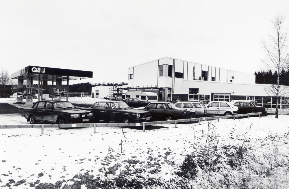 Upplands motor AB med adress Smidesvägen 2 vid Angarnsvägen. Företaget säljer volvo- och renaultbilar samt har en reparationsverkstad. På området finns också en bensistation, Q8. I förgrunden står flera bilar parkerade