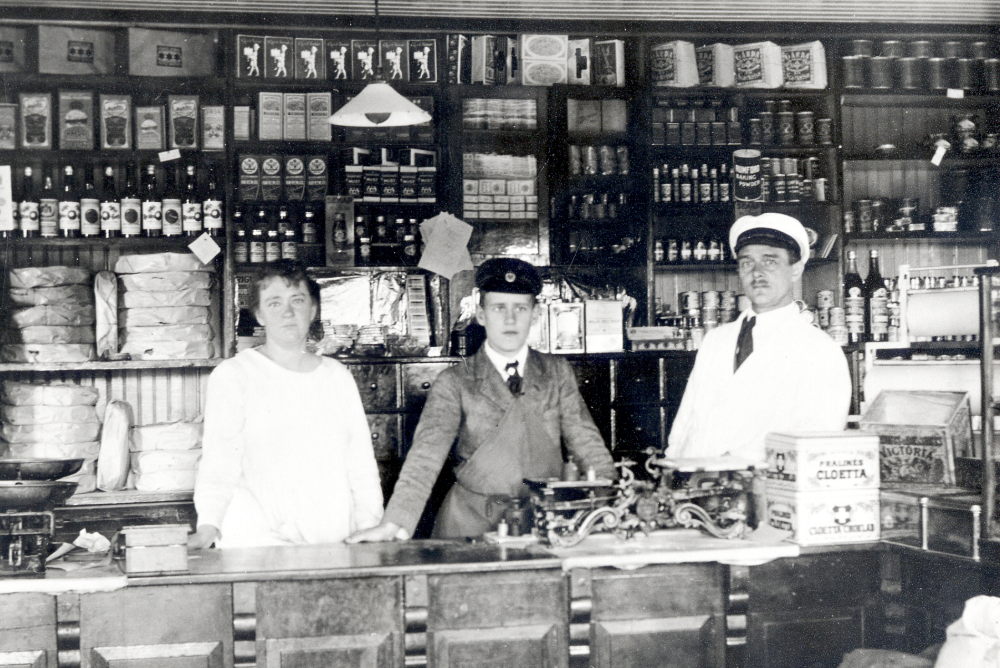 Lelkis affär låg i korsningen nuvarande Angarnsvägen och Åbyholmsvägen. Affären byggdes 1912 av bröderna John (Johannes) och Oscar Lelki. Oskar Lelki står vid disken t h, t v hans hustru Mia Lelki och i mitten expediten John Johnsson född 1906. Johannes Lelki var morfar till John. 1926 övertogs affären av Christian Sjögren.
Mer om affärer och handelsbodar finns att läsa i "Lanthandlare i vallentunasocknarna vid Roslagsbanan".