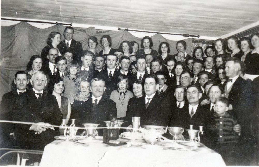 Frösunda skytteförenings årsfest i mars 1932 hemma hos Sven Helgöstam på Stora Vreda gård. Genom att från vänster dra en linjal åt höger är följande personer med på festen:  Axel Franzén, O Åkerlind, Edith Helgöstam, Sven Helgöstam, Sanna Céwe, Fru Hansson, Karl-Erik Helgöstam, Allan Céwe, Helge Stolpe, Kerstin Helgöstam, okänd vid fotoskada, Erik Franzén, Tyra Lundkvist, fabrikör Albin Hansson, Bengt Helgöstam, Naimi Lundkvist, Evert Eriksson, Karl Andersson delvis skymd, Gudrun Helgöstam, Helge Jansson, Svea Lundkvist, Birger Pettersson Torsholma delvis skymd, okänd delvis skymd, Signe Helgö-stam, Maria Franzén, Sven Eriksson, Karin Helgöstam, Edvard Thorell, Thor Salvin, Bertil Lindecrantz, Sven Hermansson, Alice Helgöstam, Erik Holmsten, Svea Helgöstam, Sven Wahlström, Margit Helgöstam, Gustaf R Åhman, Evert Fridh, Vilhelm Vred, Harry Eriksson delvis skymd, Johan Andersson, Karin Nyberg, Arnold Jansson Fridh, Leonard Andersson, Signe Andersson, okänd skymd, Helge Andersson, Sixten Helgöstam, Astrid Johansson, Zackeus Andersson, Gösta Andersson, okänd, Elsa Johansson och Linnea Stolpe