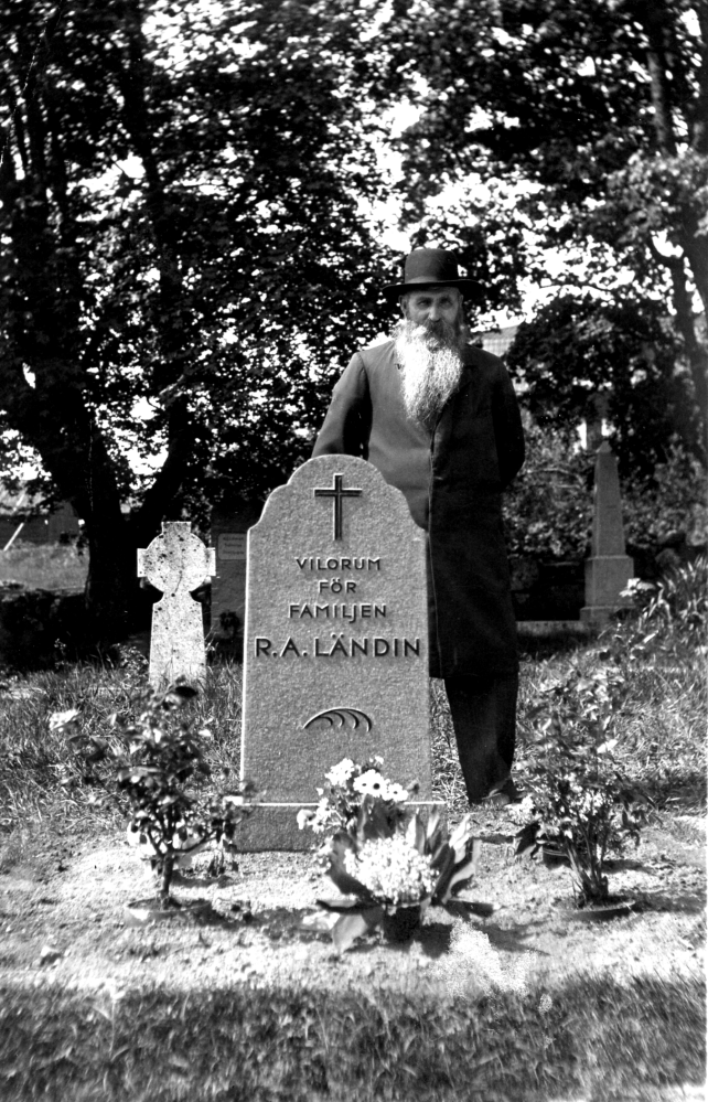 August Ländin vid familjegraven på Kårsta kyrkogård.  Ländin var fjärdingsman och torpare på Backatorp under Backa gård i Kårsta och levde 1963-1935.  August var gift med Emma Augusta, som levde 1866-1933,   fotografiet med maken vid graven är förmodligen taget 1933 efter hustruns begravning.  Paret fick 11 barn tillsammans.