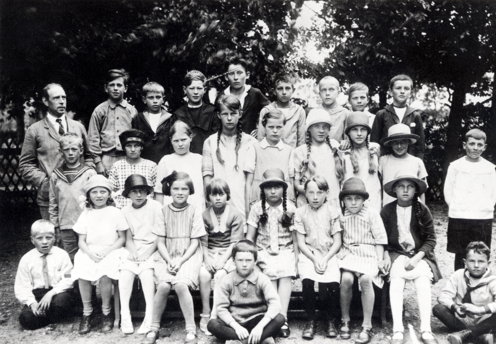 Läraren Gustaf Sundman tillsammans med skolbarnen utanför Frösunda skola. Nedersta raden fr v: Holger Johansson, Ella  Stolpe, okänd, Marianne Gustafsson, Vivi Bergman, Gustaf Åkerblom,  Ann-Marie Jansson, Mary Jansson, Svea     Andersson, Sonja Fundell och Åke Ludvigson. Andra raden fr v Bengt Karlsson, okänd, Hellevi Larsson, Helny Ekström, okänd, Hedvig Johansson  okänd, okänd, okänd. Tredje raden fr v: Karl-Erik Helgöstam, Eivan Johansson, Arthur Öhrlund,     okänd, Sven Wredh, Nils Pettersson, Seth Stolpe, och Gustaf Jansson Thorsaeus    Fotografiet upphittat i ett skåp i Hjälmsta skola. Efterlyst i DN runt stan 860911,svar från Rut Ekstedt 860918.