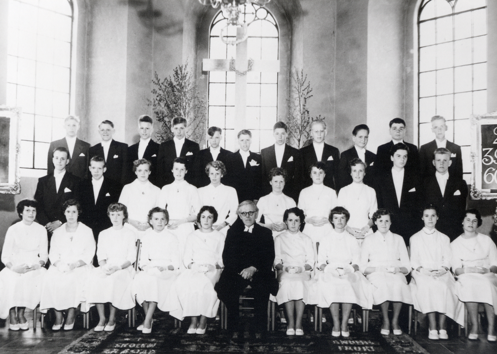 Konfirmation i Vallentuna kyrka. I koret sitter fr v  i bakre raden Lars Venngren, Ove Holm, Björn Ek, Sten Åslund, Antero Rynenen, Bengt Karlsson, Åke Jansson, Bertil Hofgren, Georg Böling, Yngve Larsson och Berhold Frölin. Mellanraden fr v Rune Lund, Hans Hellstrand, Gun-Britt Karlsson, Kerstin Berg, Lillemor Åsberg, Inger Allenius, Berit Karlsson, Yvonne Karlsson, Lennart Jirstedt  och Ingvar Lundqvist.  Nedersta raden fr v Marianne Leverin, okänd, Eivor Åman, Anita Johansson, okänd, kyrkoherde Sven Vängby, Maj-Britt Lundqvist och Anja Helenius