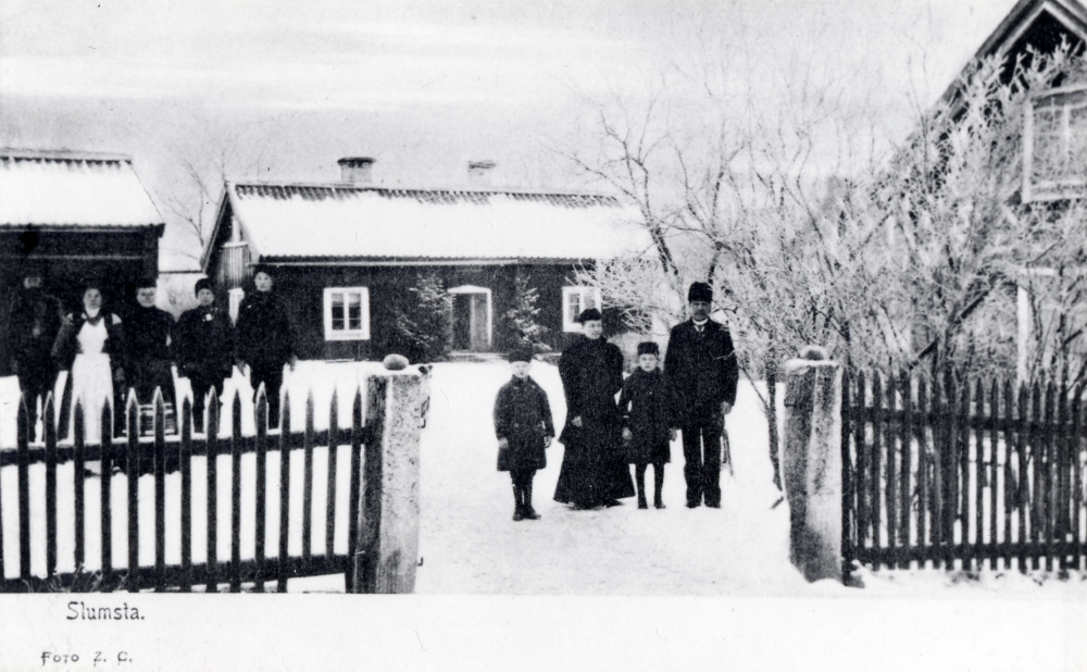 Slumsta gård i Lindholmen. I grindhålet står fr v fostersonen Nils Lindberg, Emma Johansson, sonen Emanuel 'Manne'Johansson och Bernhard Johansson. Tjänstefolket t v. Slumsta var först en vanlig bondgård som senare blev handelsträdgård. Bostadsområdet Skärholmen är byggt på Slumstas mark.