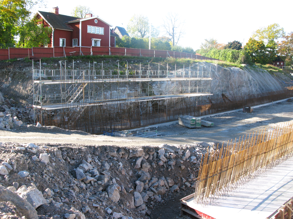 Arbetet med sociodukten över Väsbyvägen fortsätter. Väsbyvägen har fått ny sträckning närmare kyrkan. I bakgrunden syns prästgården och Vallentuna kyrka.