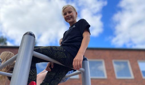 Elev sitter på klätterställning på skolgård Karlslundsskolan