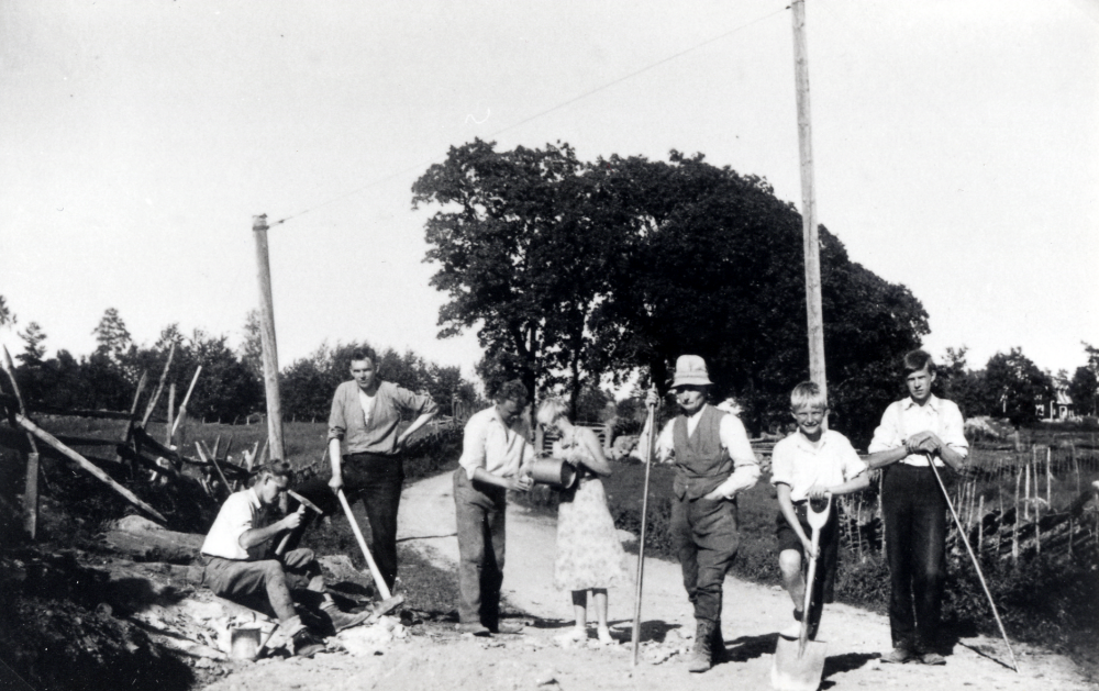 Vägunderhåll på Lingsbergsvägen vid Björkhaga i Vallentuna. På 1930-talet bestämdes av markägarna skulle underhålla vissa sträckor av Lingsbergsvägen.  Här arbetar familjen Brunnberg, som hade sitt sommarställe på Björkhaga, gamla Lingsberg småskola.  Fr v syns  Melker,  Martin, Melkers dotter Birgit, fadern Edvard,  Maurits son Lars och Malte, alla med efternamnet Brunnberg.
