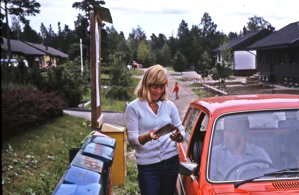 En arbetsdag med lantbrevbärare Mikael Mattsson. Lantbrevbäring i Rocksta; Agneta Gustavsson i Rocksta får post av lantbrevbärare Mikael Mattsson. Agneta arbetar på lärarförbundet och bor i rödbruna huset till vänster. Hennes man Dick arbetade som bilmekaniker och har en liten verkstad på gården.