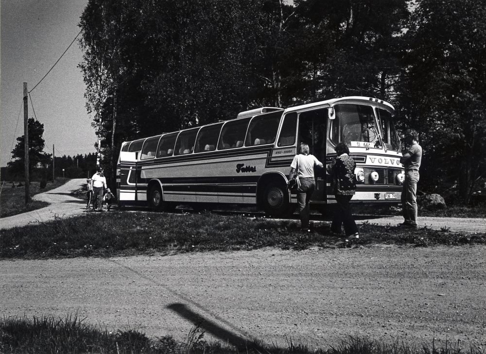 En buss från Vallentuna buss parkerad i vägskälet där vägarna från Viby och Vaxtuna möts. Foto från Hembygdsrundturen för nyinflyttade i Vallentuna, arrangerad av Kulturnämnden och hembygdsföreningarna i Vallentuna. Passagerararna stiger på igen efer att ha sett Kööhögen