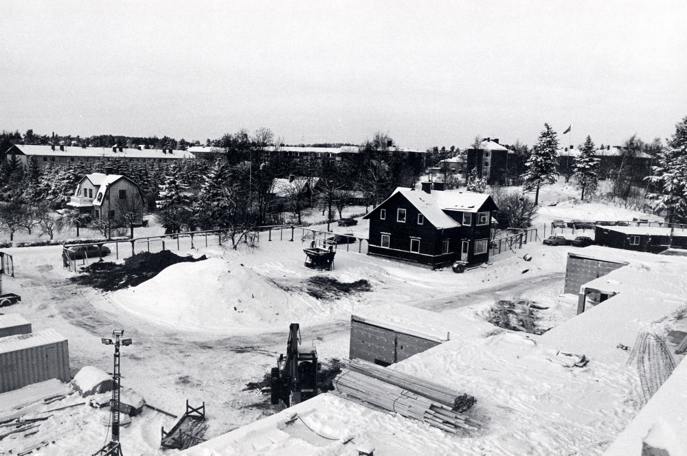 Förvaltningshuset Tärningen byggs. Foto över omgivningarnas från det ännu ej färdigbyggda huset mot väster. T v syns K E Karlsson gamla villa samt det mörka huset en av tvillingvillorna den andra villan revs inför husbygget. Husen på höjden i bakgrunden är flerfamiljshus längs Mörbyvägen