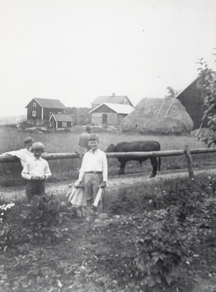 Ekeby gård med svinhus och tvättstuga.  En stor halmstack syns t h.  Nr 2 från vänster heter Gustav Grandin
