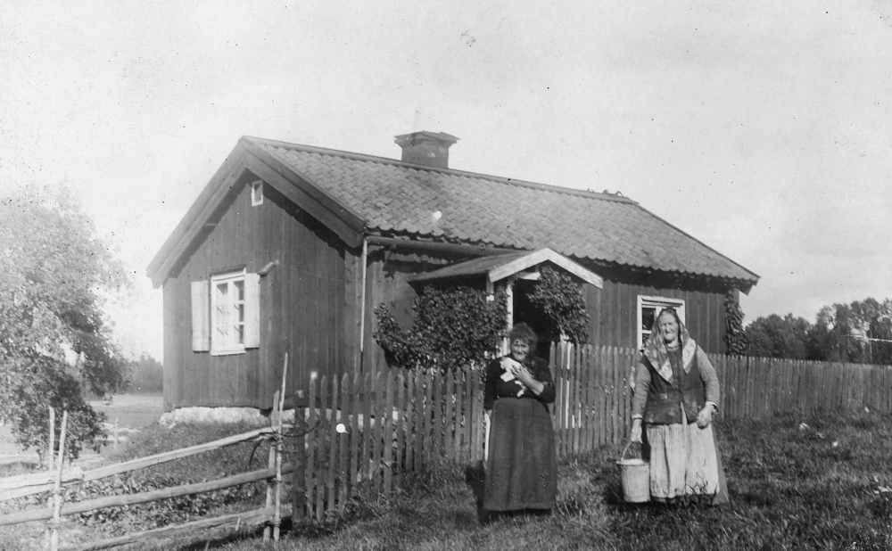 Utanför torpet Molnbylund står Hilda Johannesdotter född i Gränna landsförsamling 1856 till höger. Kvinnan till vänster är okänd. Hilda Johannesdotter bodde i torpet fram till sin död 1930.