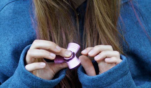 Tonårstjej snurrar på en fidgetspinner.