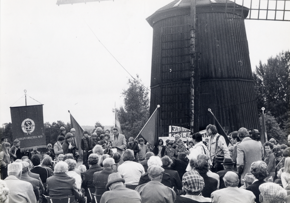 Centerpartiet  har  valmöte  vid  Väsby kvarn  Här står centerledarenn  Thorbjörn Fälldin  i talarstolen framför en stor mängd åhörare. Bakom Thorbjörn Fälldin är kvarnen. Ett  standar  från  SLU Markim-Orkesta avd  syns t h.