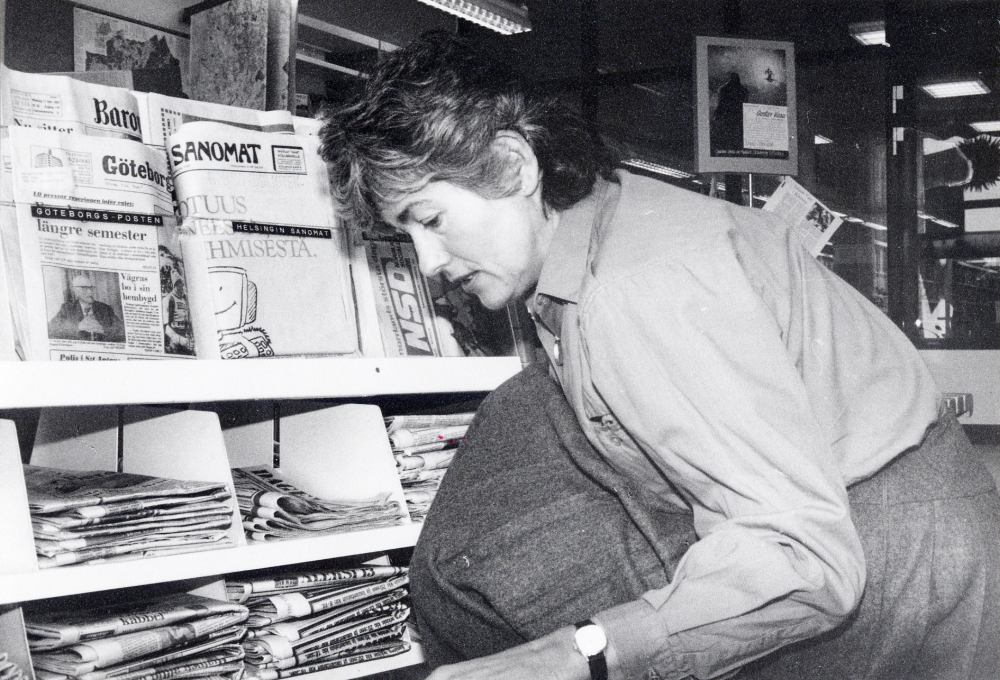 Kerstin Berglund sorterar dagstidningar på tidningsvagnen i foajén i Vallentuna bibliotek