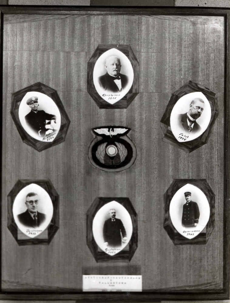 Tavla med fotografier över stationsföreståndare, stinsar, vid Vallentuna järnvägsstation. Sten Ullermo gjorde tavlan till sin chef.  Fotografierna på stinsarna fick han av chefen. Tavlan hängde i  stationshuset till huset revs den 4 augusti 1972. Tavlan hänger nu (1989) i Åbybergskyrkans Café Nyponstigen. Uppgift om fotoår saknas.