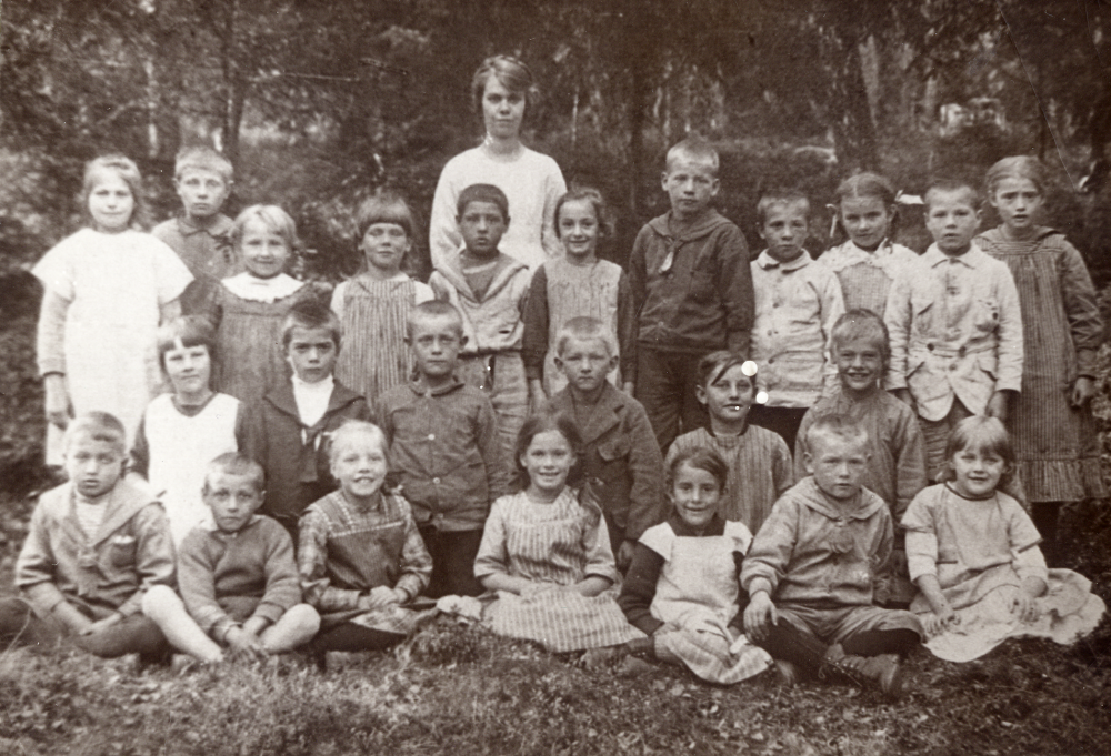 Lärarinnan  Lilly Andersson-Fall  tillsammans med skolbarnen vid  Berga skola  Lilly Andersson gifte sig med evangelisten  Fall  från Filadelfiaförsamlingen.    Lilly Karlsson skriver: 'Det blundande busfröet till vänster om lärarinnan är jag!'