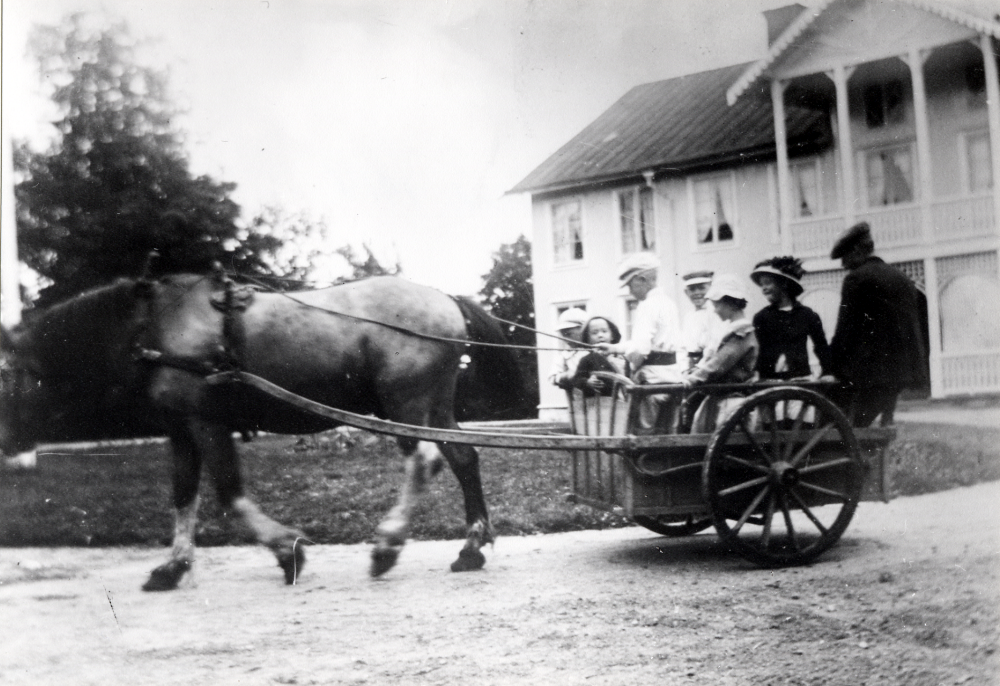Häst och vagn vid Backa gård.  Hästen Nocken drar en liten vagn.  I vagnen sitter fr v Erik Lindgren, Gösta Åkerlund, ? Åkerlund, Gösta Kuhlman, Greta Lindgren, Ansa Åkerlund och Sigge Lundberg.  Barnen Lindgrens far är Sven Lindgren, ägare till Backa, Åkerlunds är sommargäster