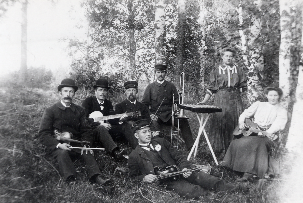 Musik i det gröna Spelgänget Fr v Karl Andersson från Nybygget med fiol Rickard Lind med gitarr Frans Oskar Johansson Blinkarby mjölnaren från Bromseby på marken framför Helmer Runnström med ventiltrombon sittande mot björken med gitarr Ester? Runnström syster till Helmer H, och vid cittran Hulda Johansson dotter till Frans Oskar Johansson