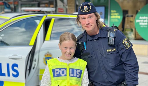 Barn och polis står bredvid varandra framför en polisbil.