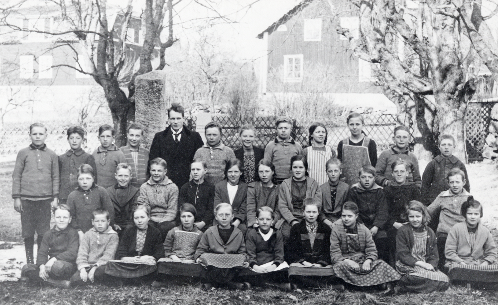 Läraren Halvar Hedler tillsammans med skolbarnen utanför kyrkskolan i Kårsta vårterminen 1926. Bakre raden fr v Helge Söderström, Georg Åman, Lennart Olin, Sonja Hammar, läraren Halvar Hedler, Erik Johansson, Karin Andersson, Åke Björklund, Anna-Lisa Enderberg, Helny Ahlgren, Tor Watz och Biger Jansson. Rad 2 fr v Harry Andersson, Gunnar Åkerström, Helge Andersson, Sonja Söderström, Gulli Larsson, Anna-Lisa Larsson, Astrid Matocka, Verna Johansson, Artur Törnkvist, ? Nilsson och Åke Edlind. Rad 3 Börje Lundin, Artur Eriksson, Edit Johansson, Greta Andersson, Gunborg Öman, Elsa Karlsson, Karin Karlsson, okänd, Anna Söderström och Sonja Jonsson