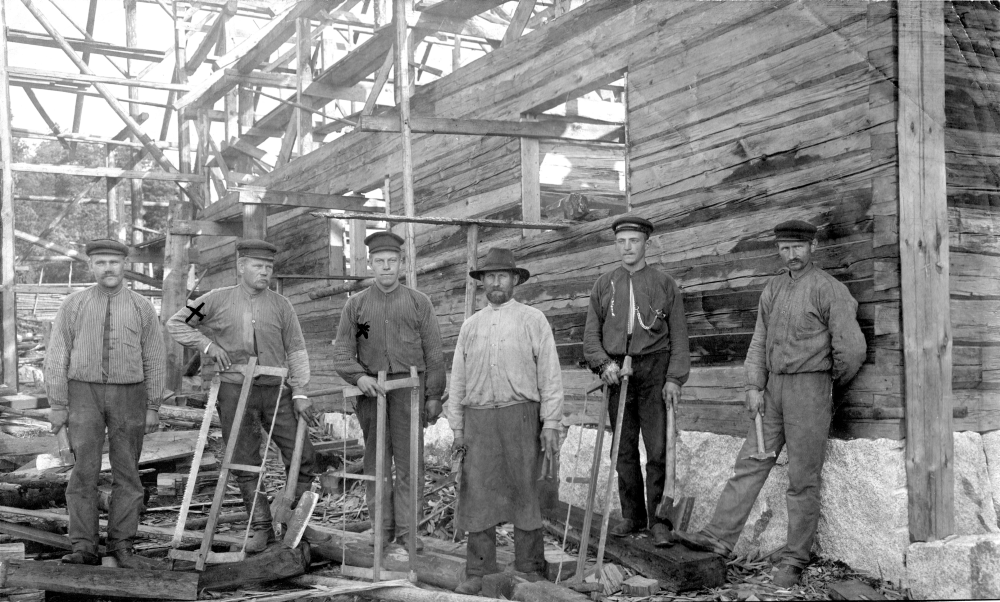 Byggmästare Rickard Johansson från Fridaberg i Markim står som nummer två från vänster. Bredvid honom till höger står Filip Johansson från Glasskåpet i Lilla Söderby, Lunda. De övriga personerna är okända. Bilden är antagligen från något husbygge i Lunda socken. 
Originalet tillhör Lunda hembygdsförening.