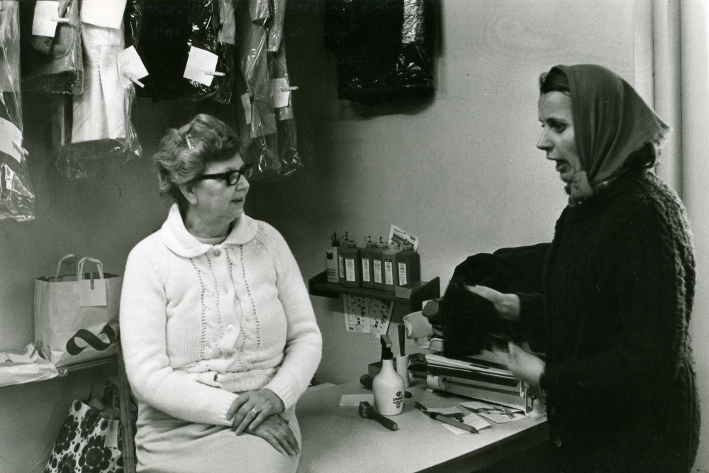 Interiör från Vallentunatvätten, tvätteriet vid Vallentunasjön. Föreståndarinnan och en kund.

•Fotografiet ingår i bildserien ”Vardagsliv i Vallentuna kommun” av Rachael Gough-Azmier & Gunilla Blomé, Haga Studios HB.