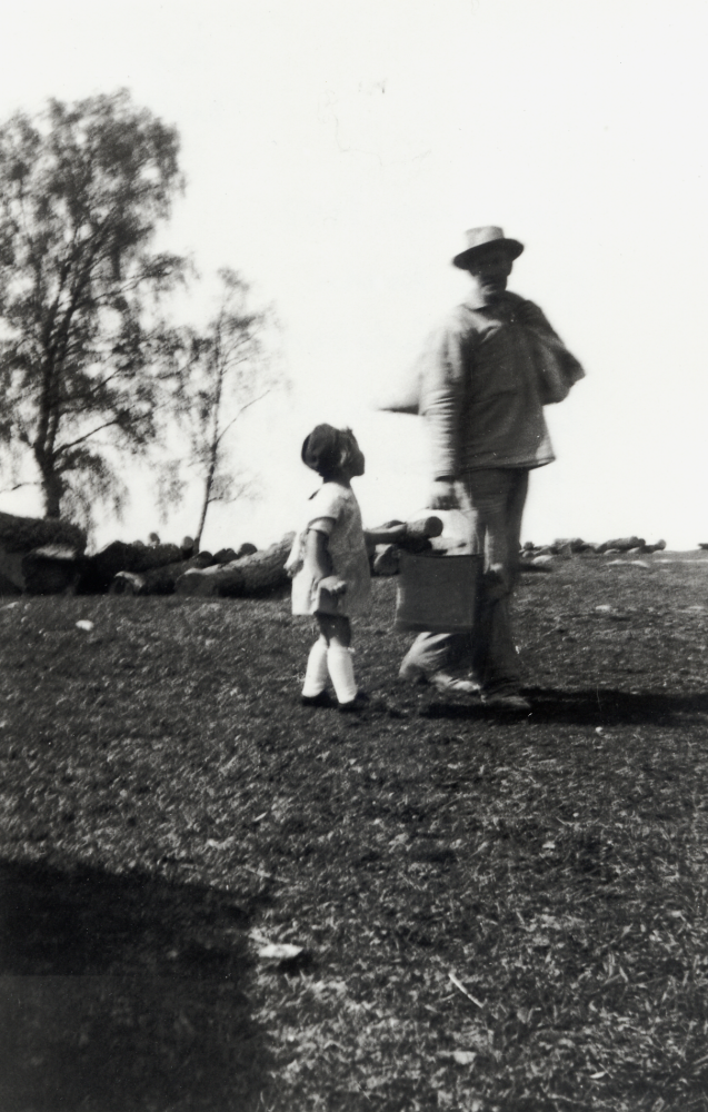 Mjölnaren Werner Hedlund vid Granby kvarn och såg på väg över ladugårdsbacken sommaren 1942.  Han är på väg till svinhuset med gröpe i säcken och svinmat i hinken.  Bredvid går barnbarnet Anita