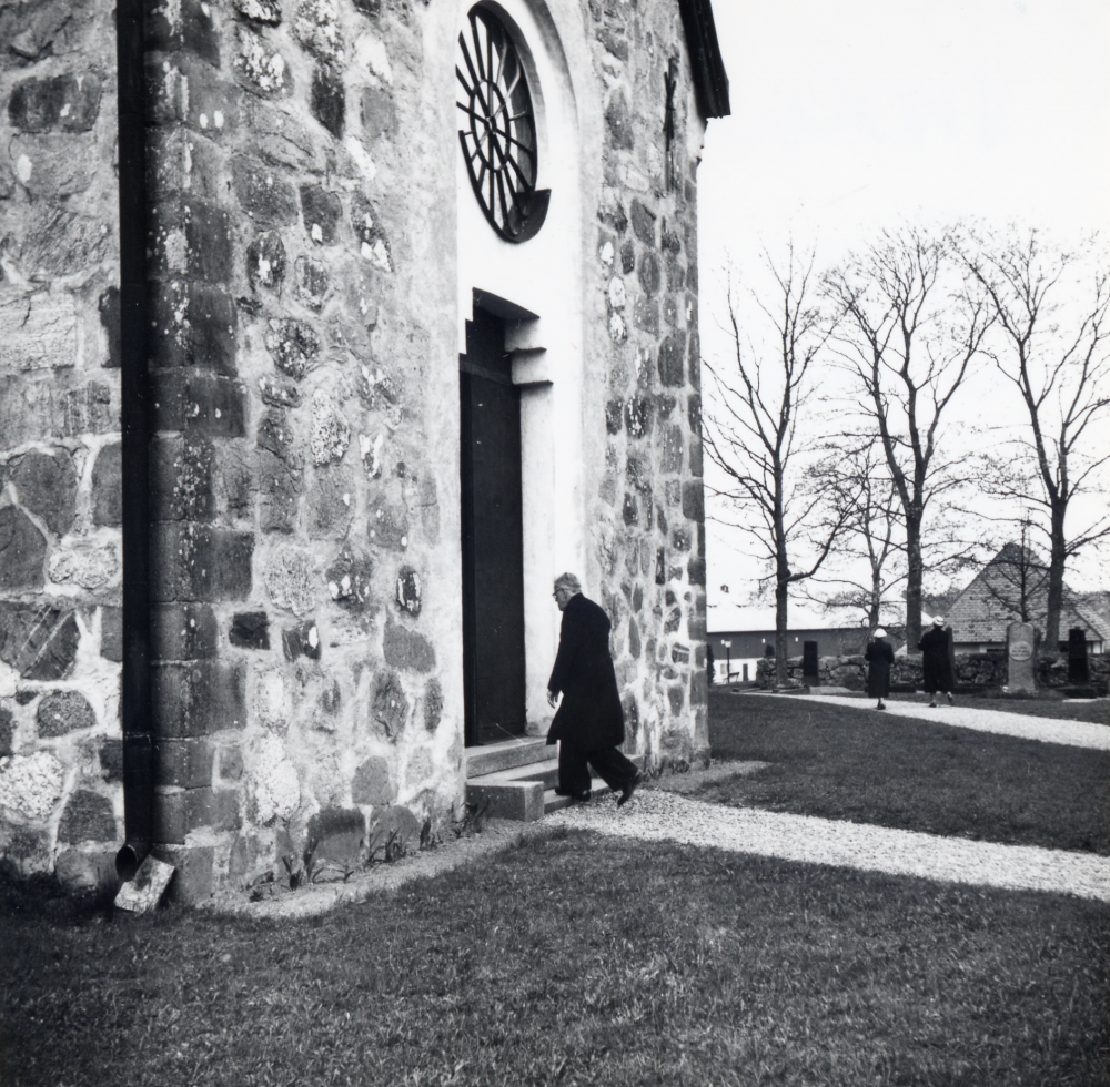 Kontraktsprost Sven Vängby på väg in genom västra ingången till Vallentuna kyrka. I bakgrundens ses gravkapellet
