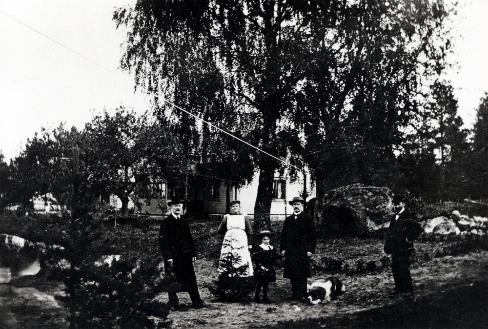 Lottenlund i Vallentuna. Fastigheten (Åby 1:71) som uppfördes 1912, ligger i hörnet av Angarnsvägen och Åbyholmsvägen. Här öppnade Joh. och Oskar Lelki en diversehandel. I bildens mitt står John (Johannes) Lelki och håller dottern Margareta i handen. Bredvid ligger hunden Bob. I affären drevs Lelki handel
Se Lanthandlare i vallentunasocknarna vid Roslagsbanan
Uppgift om fotoår saknas, men troligen första delen av 1900-talet.