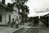 På perrongen vid Lindholmens station står en grupp vuxna och några barn med cykel.