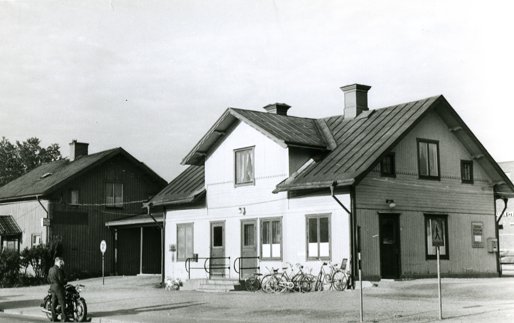 Under senare år hade tapetserare Sandberg sin affärslokal i "Flugan".  T h skymtar Maskin-Tellus, som tillverkade rullbanor för industribruk, numera Vallentuna gymnasium.  Flugan brann ner 1970 och stationshuset revs 1971/72 inför byggstarten av Tunahuset.