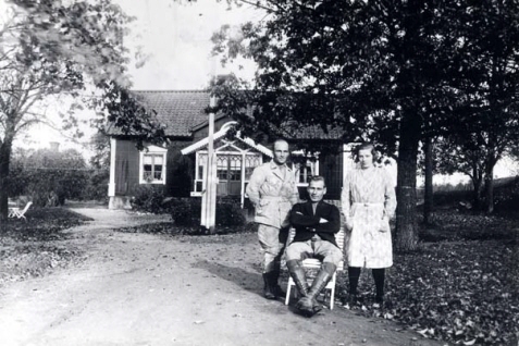 En grupp människor som står/sitter framför ett hus