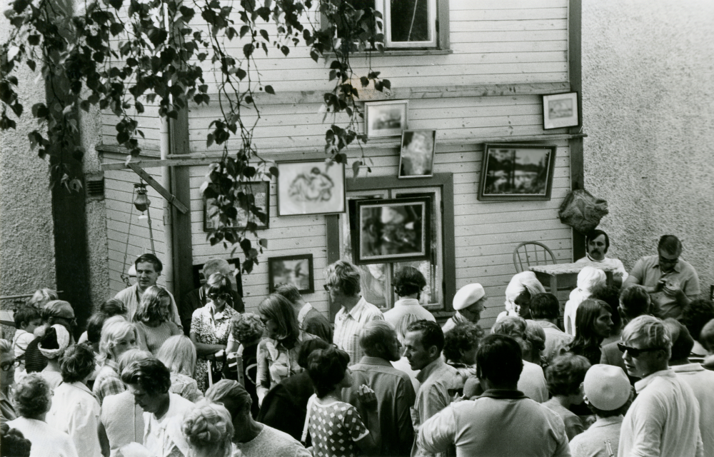 Auktion på Åbyholms gård. Många besökare syns i förgrunden. Några tavlor är upphängda på husfasaden.

•Fotografiet ingår i bildserien ”Vardagsliv i Vallentuna kommun” av Rachael Gough-Azmier & Gunilla Blomé, Haga Studios HB.