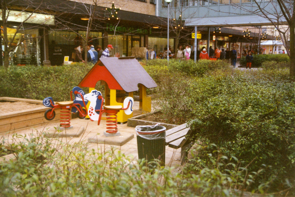 Lekplats på Tuna torg. Juldekorationer hänger på fasaden.