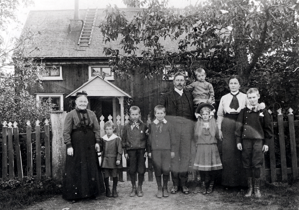 Mellangården i Toftesta.  Mormor Sofia Pettersson står längst t v. Gårdens ägare är Gustaf Almén och hans hustru Maria. Maria var före giftermålet lärarinna i Lilla Garn. Fr v står barnen Bengt * 1907, Torsten * 1903, Lennart * 1902, Blenda * 1905, Erik * 1900, på faderns arm sittter Tore * 1908.  Yngsta dottern Maria Elisabeth föddes 1913